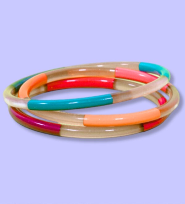 Jonc 5mm colorés mix Jonc en métal de 5 mm d’épaisseur avec un mélange de couleurs vives : rouge, turquoise, orange et beige, présenté sur fond violet.