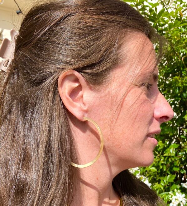 Image d’une femme portant des créoles en corne, ajoutant une touche élégante à son look. Parfait pour les accessoires de mode naturels et tendance.