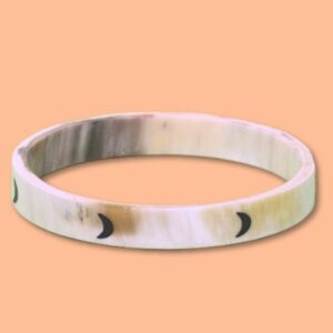 Jonc en corne de 10 mm avec motif de lunes noires sur fond beige, présenté sur un fond orange.