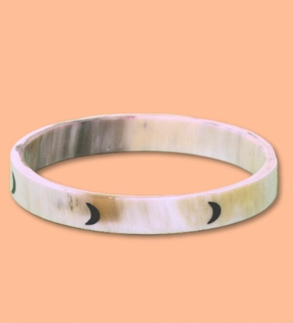 Jonc en corne de 10 mm avec motif de lunes noires sur fond beige, présenté sur un fond orange.