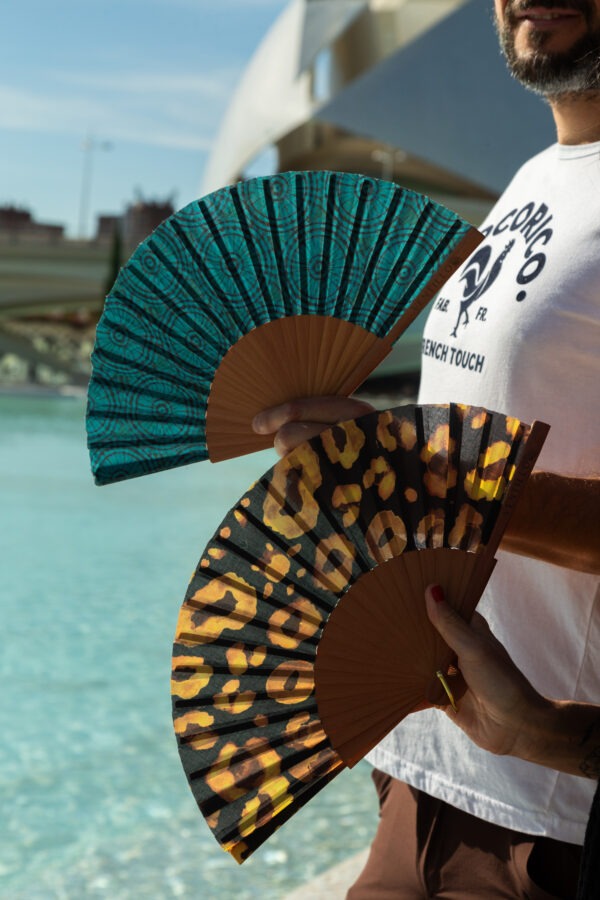 Découvrez notre collection exclusive d’éventails, mettant en avant deux motifs distincts et captivants : l’un arborant un design léopard audacieux et l’autre un motif géométrique turquoise intrigant. Ces éventails sont fabriqués à partir de matériaux de haute qualité, combinant un cadre en bois robuste avec des lames en tissu durable. Parfaits pour ajouter une touche d’élégance et de fraîcheur lors des journées chaudes, ces éventails se distinguent par leur esthétique unique et leur fonctionnalité. Que vous optiez pour le motif animalier audacieux ou le design géométrique sophistiqué, ces éventails sont des accessoires indispensables pour rester cool et stylé.